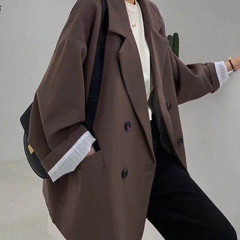 Woman wearing a brown double-breasted relaxed blazer over a cream top